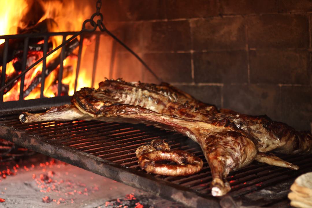 A Lamb and wild boar sausage on a grill with lots of fire.